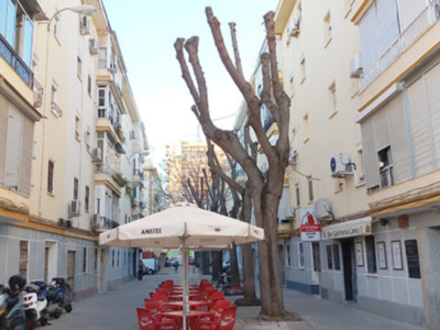 Elegante calle de edificios modernos con sillas rojas y toldo beige.