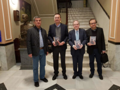Cuatro hombres posan con sus premios en un entorno formal, frente a una escalera y una estatua.