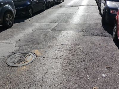 Manzana de hierro en la calle, entre dos vehículos estacionados.