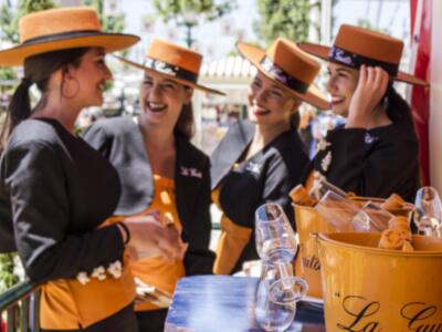 Cuatro camareras sonrientes con sombreros y uniformes de color naranja, posiblemente en un evento o restaurante.