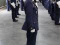 Fotografía de una mujer uniformada en el centro, rodeada por un grupo de hombres también vestidos con uniformes militares. La imagen parece ser de una ceremonia o desfile militar, posiblemente en un hangar.