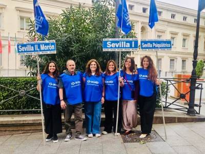 Representantes de ACAIP-UGT con carteles de los centros penitenciarios de Sevilla.